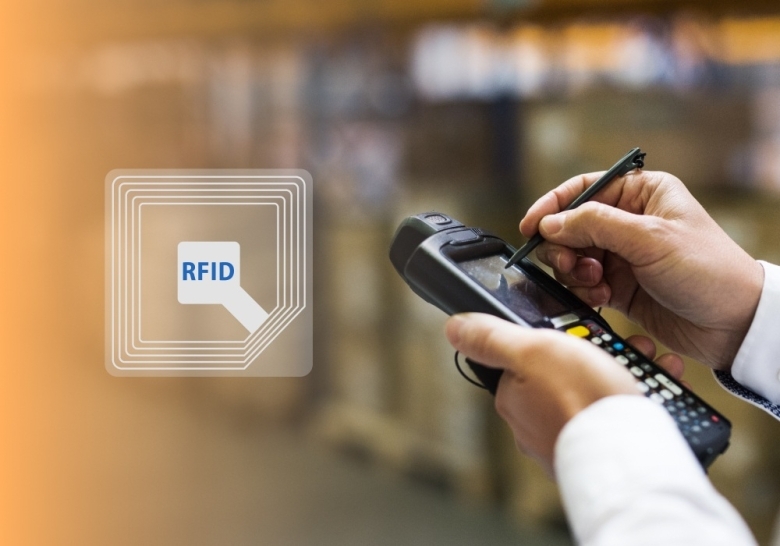 Close-up of hands using a stylus on a handheld RFID scanner in a warehouse, with a digital RFID icon overlay on the left side of the image.